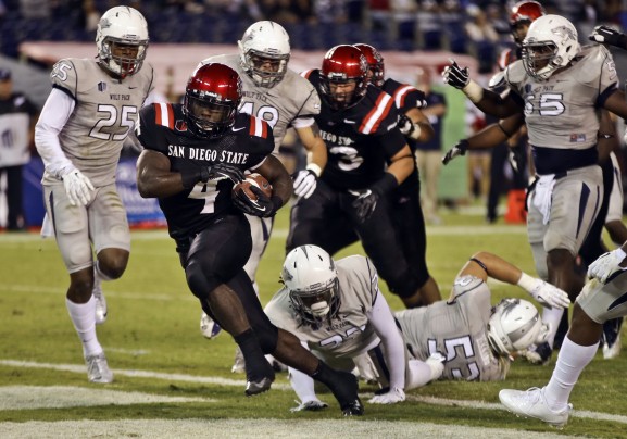 San Diego State running back Adam Muema rushes through the Nevada Wolf Pack defense for a gain on Friday night. The Aztecs went on to win in overtime 51-44. (Photo via Lenny Ignelzi of the AP)